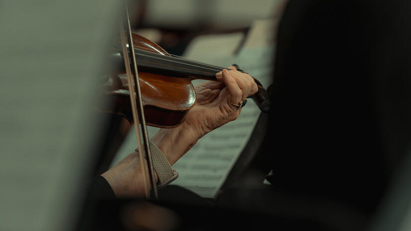 The craft of performance — Indian River Pops Orchestra Close view of a musician’s hand playing a violin during an orchestra rehearsal