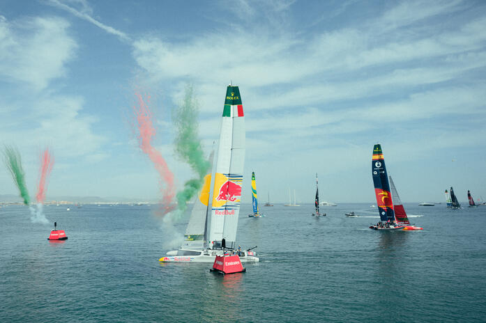 SailGP catamarans racing off Valencia’s waterfront, with coloured smoke rising beside the fleet.