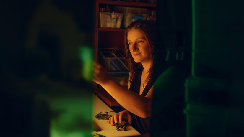 Woman working with small hand tools at a craft table in atmospheric green and amber light