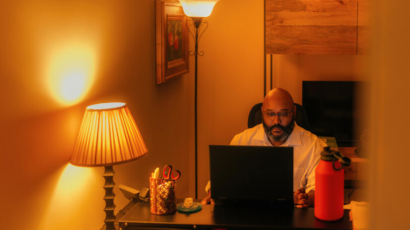 Specialist in his workspace Man working on a laptop at his desk in a warmly lit office
