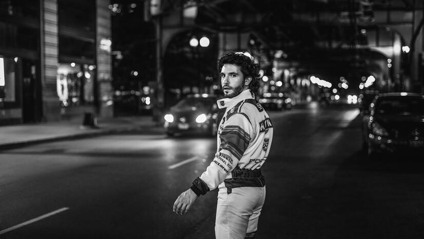 Creative campaign portrait Man in a racing-inspired outfit walking through a city street at night