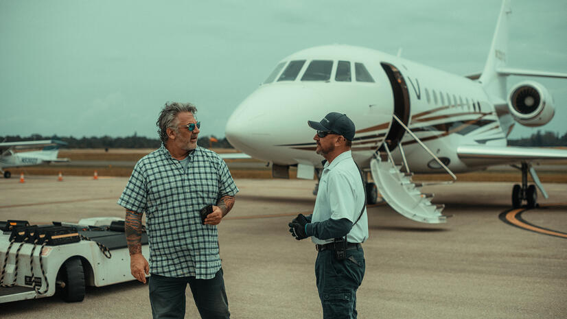 Two aviation professionals talking on an airfield beside a private jet