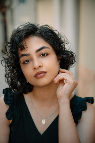Close portrait of a woman with short curly hair resting her hand near her face